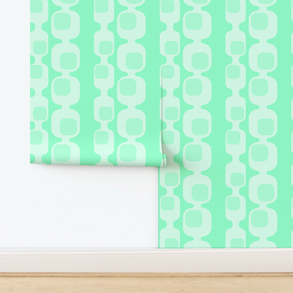 The artwork features a repeating geometric pattern of symmetrical shapes resembling elongated, curved diamonds or petals in various shades of blue and green. Each shape is split vertically with one half filled with a light blue and the other half filled with green or darker blue. The background is a light, almost pastel blue, which provides a soft yet vibrant backdrop. One of the blue shapes near the upper left contains a white starburst element, adding a focal point of brightness to the composition. The overall design conveys a modern, mid-century aesthetic with clean lines and harmonious color contrasts.